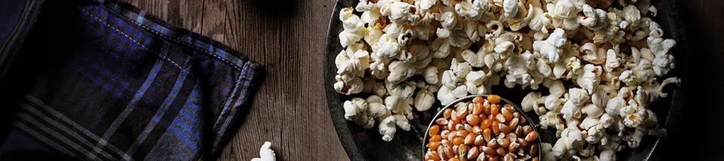 Popcorn and kernels on a dark plate.