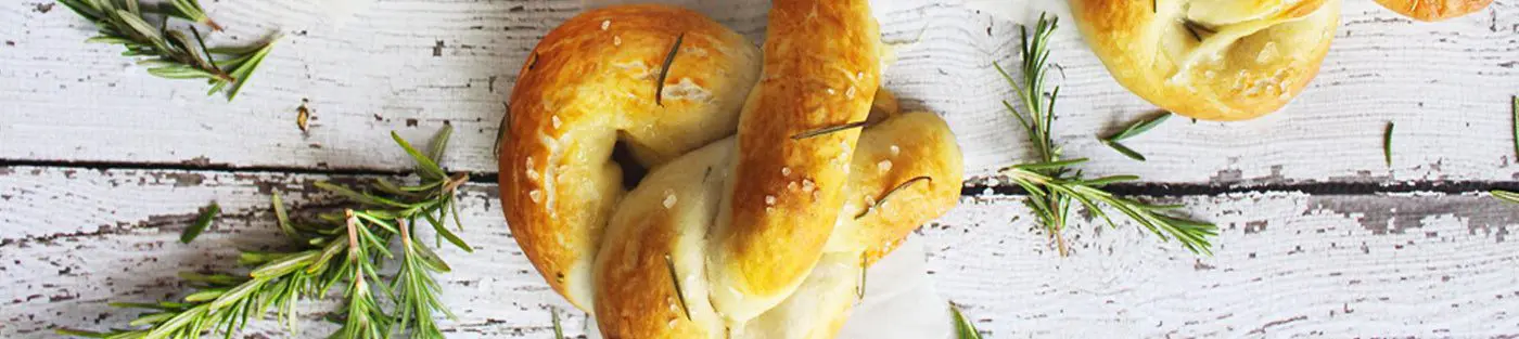 Pretzels with rosemary on rustic wooden table.