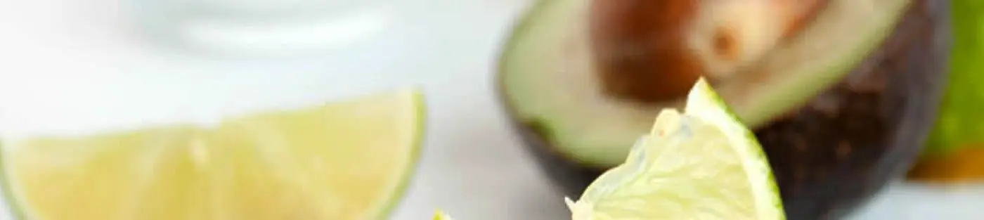 Lime wedges and halved avocado on table.
